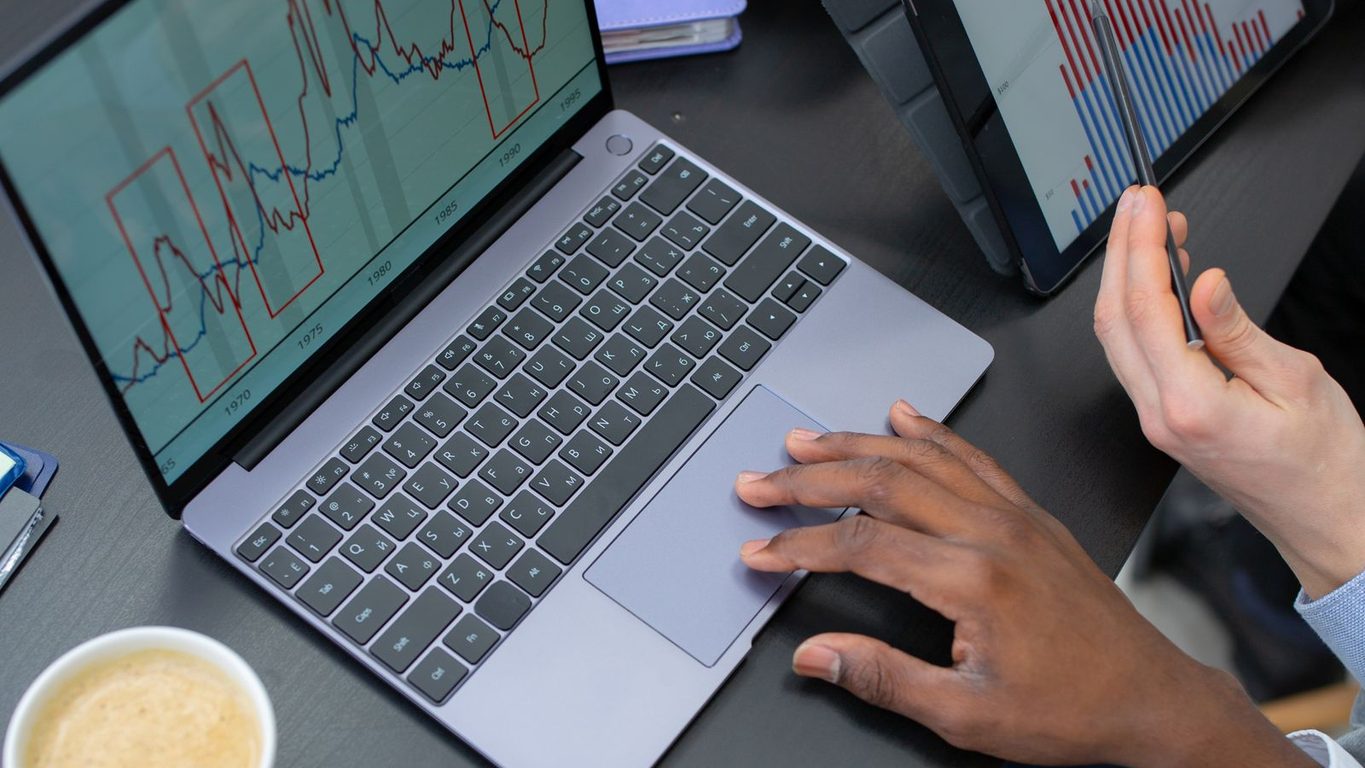 Dos personas revisando graficas de ventas en un portatil sobre una mesa de oficina