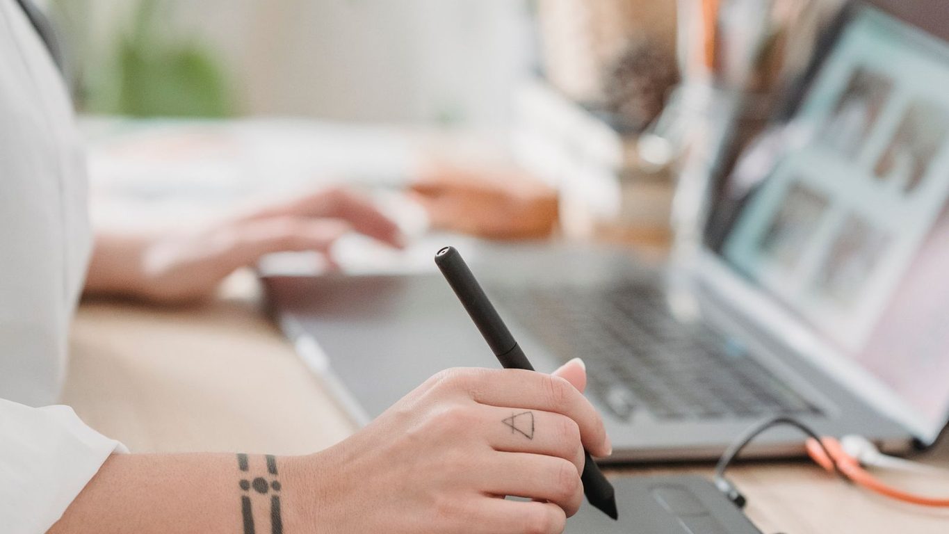 Disenadora trabajando en una pagina web con tableta grafica y portatil
